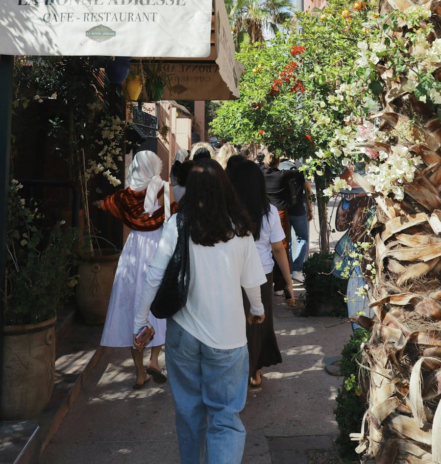 Young women walking along a shaded café street lined with bougainvillea
