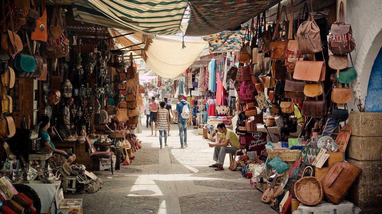A medina market lane lined with leather bags, textiles and craft stalls